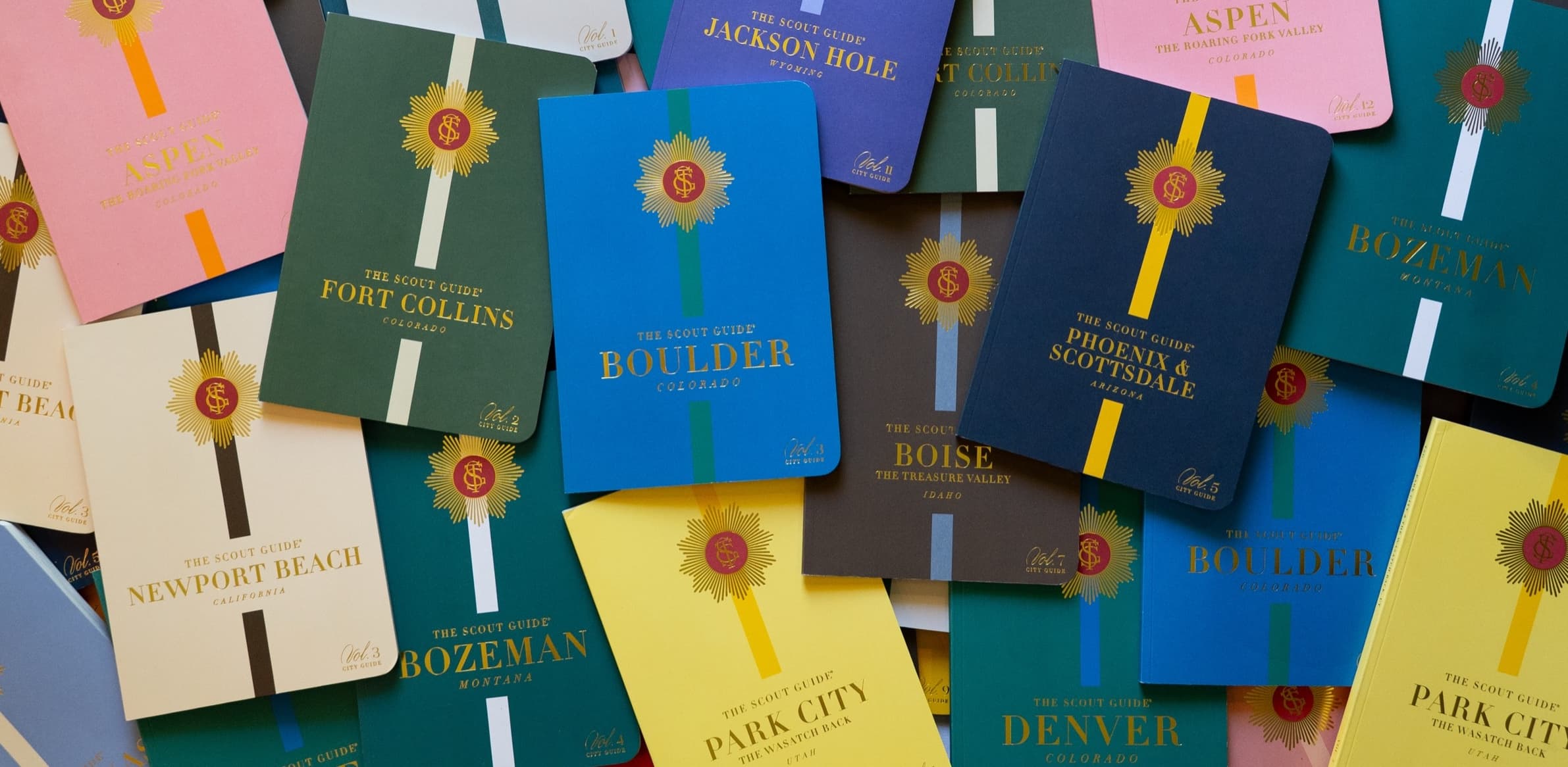 A flatlay of The Scout Guide city guides, including Boulder, Denver, Aspen and Fort Collins.